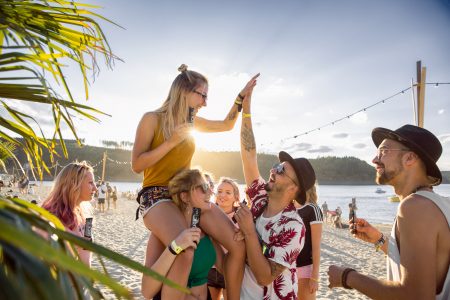 Eine Gruppe Junger Menschen feiert am Festivalstrand und halten SUCKIT in ihren Händen. A couple of young people cheering at the festival beach holding SUCKIT in their hands.