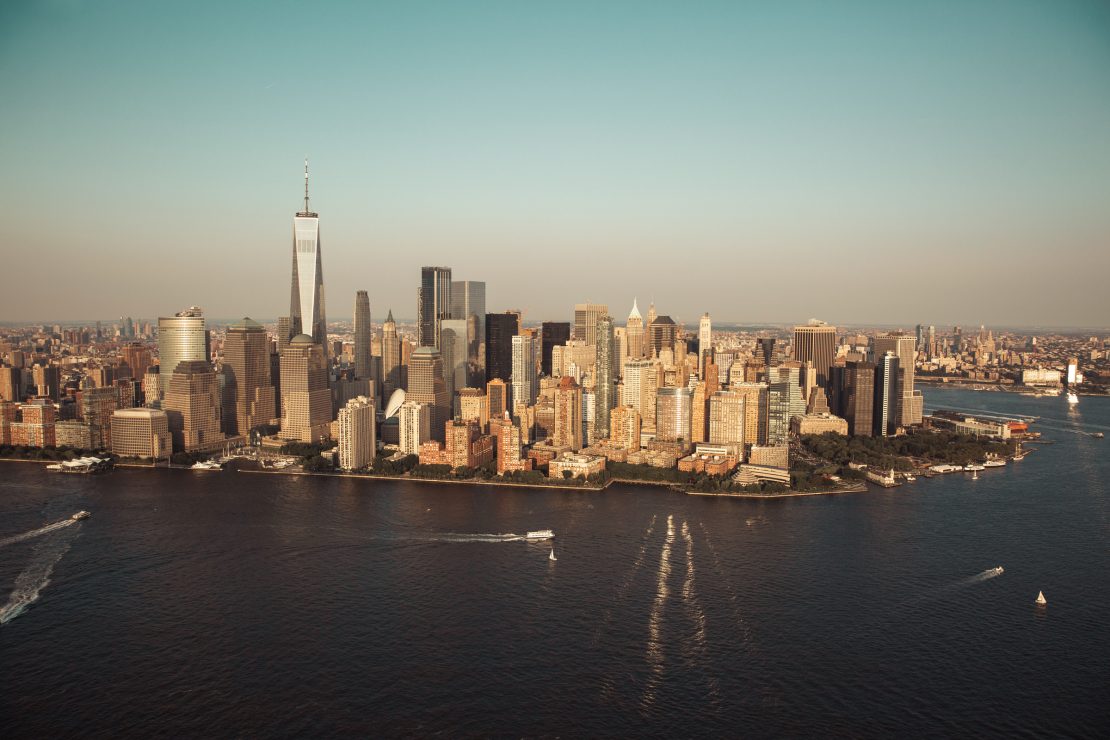 Aerial view across the water towards Lower Manhattan and One World Trade Center.